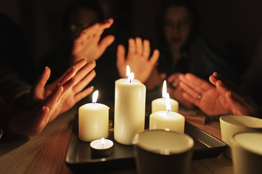 A family is crowded around a group of candles to stay warm during a blackout. In need of a whole home generator installation. 