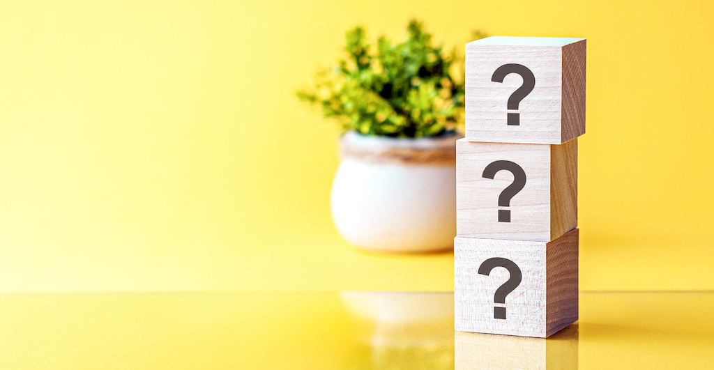 Yellow background with plant and wooden blocks with question marks. Representing FAQs about generator installs.