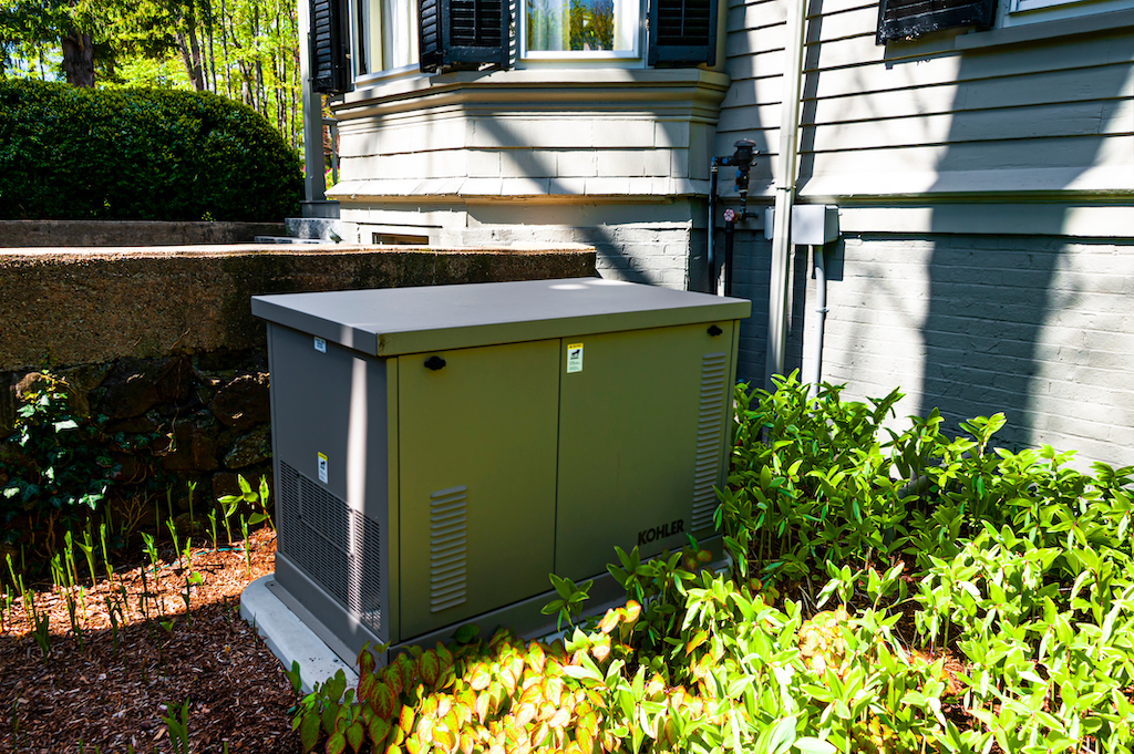 Residential standby generator surrounded by green. |  Generator Services